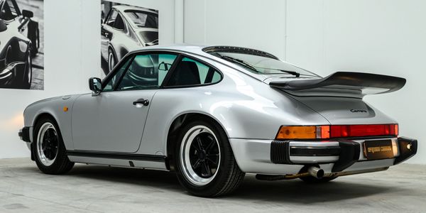 Silver Porsche Carrera with black accents in a modern showroom.