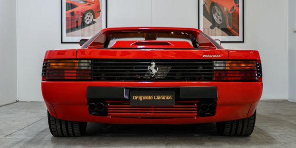Rear view of a classic red Ferrari Testarossa in a showroom.
