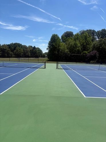 Empty outdoor tennis courts under a blue sky.