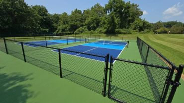 Two outdoor pickleball courts enclosed by chain-link fencing.