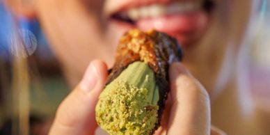 Person about to eat a green matcha-flavored cannoli dessert.