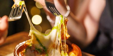 Close-up of cheesy baked dish being served with a fork.