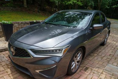 Grey Acura sedan parked on brick driveway.