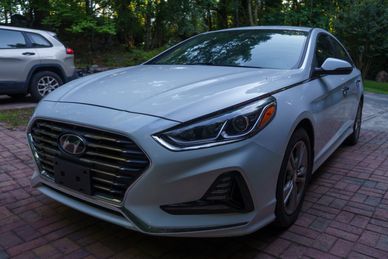 Front view of a silver Hyundai car on a brick driveway.