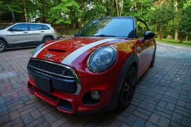Red Mini Cooper S parked on a brick driveway.