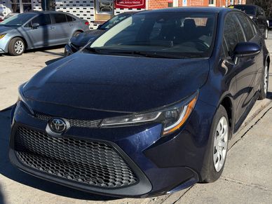 Dirty blue Toyota car parked beside a sidewalk.