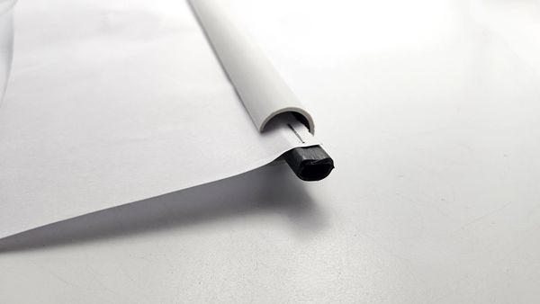 Close-up of a white paper roll with a black plastic end on a white surface.