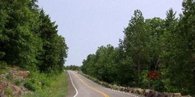 A slightly bending highway with greenery on both the sides