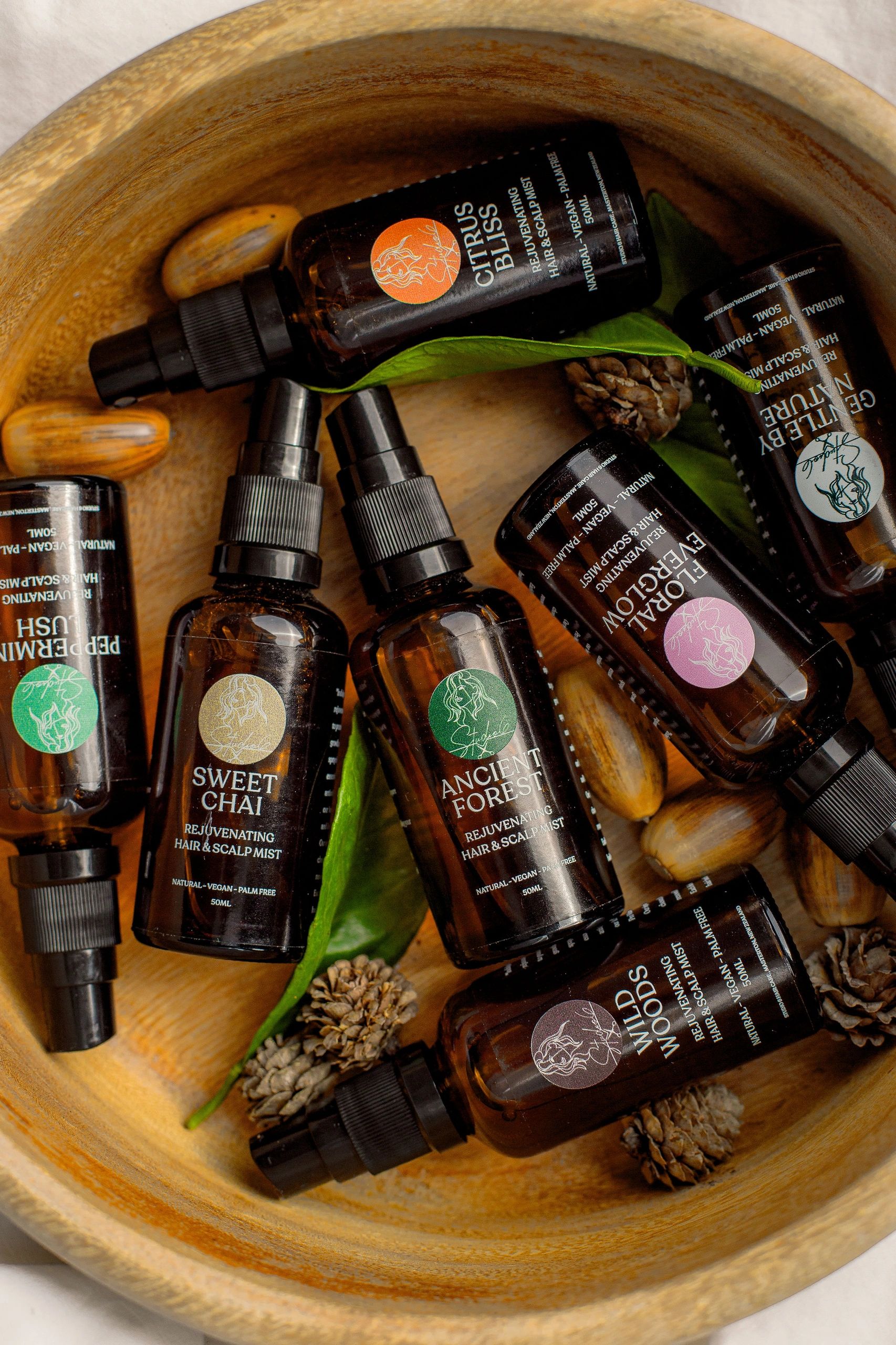 Haircare product range arranged in a wooden bowl with acorns and leaves around them.