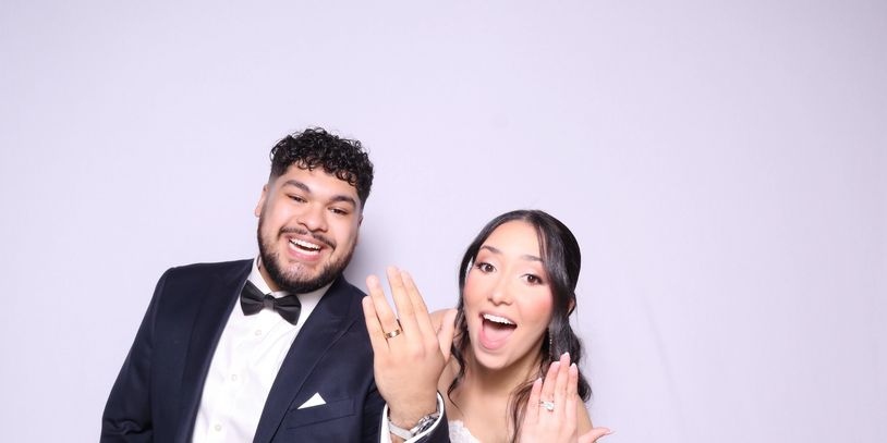 Newlywed couple joyfully showing their wedding rings to the camera.