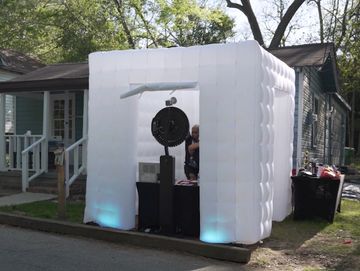 Inflatable white booth set up outdoors with audio equipment inside.