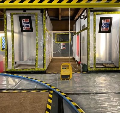 A cleanroom or containment area with sealed compartments and warning tape.