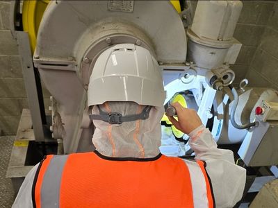 Worker in safety gear inspecting industrial machinery.