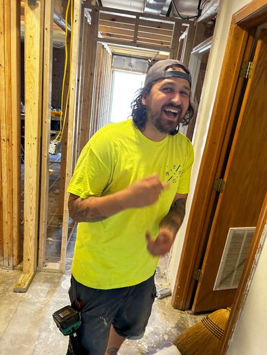 Man in construction attire laughing inside a building under renovation.