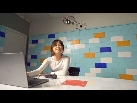 Young girl controlling a small drone indoors.
