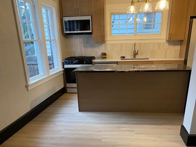 Modern kitchen with wooden cabinets and island under warm pendant lights.