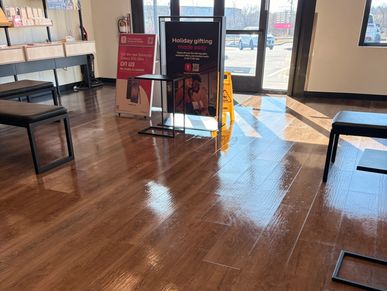 Sunlit interior of a store with wooden floors and promotional signs near the entrance.