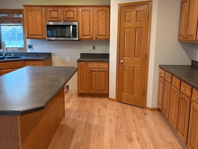 Clean kitchen with wooden cabinets and black countertops.
