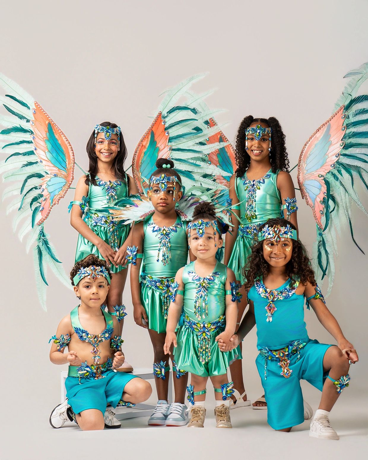 Children in vibrant carnival costumes with large feathered wings and detailed accessories.