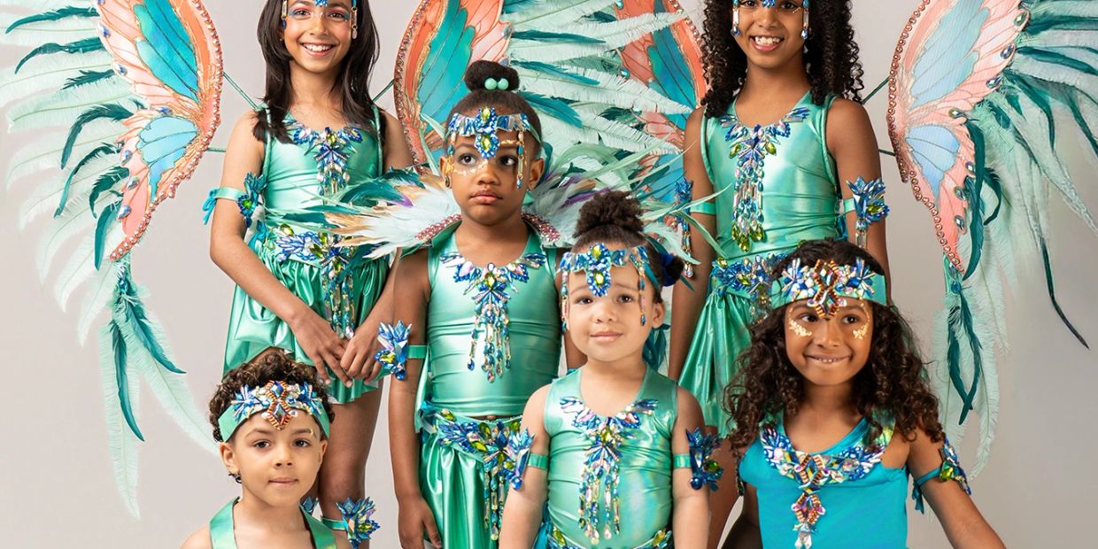 Children in vibrant carnival costumes with large feathered wings and detailed accessories.