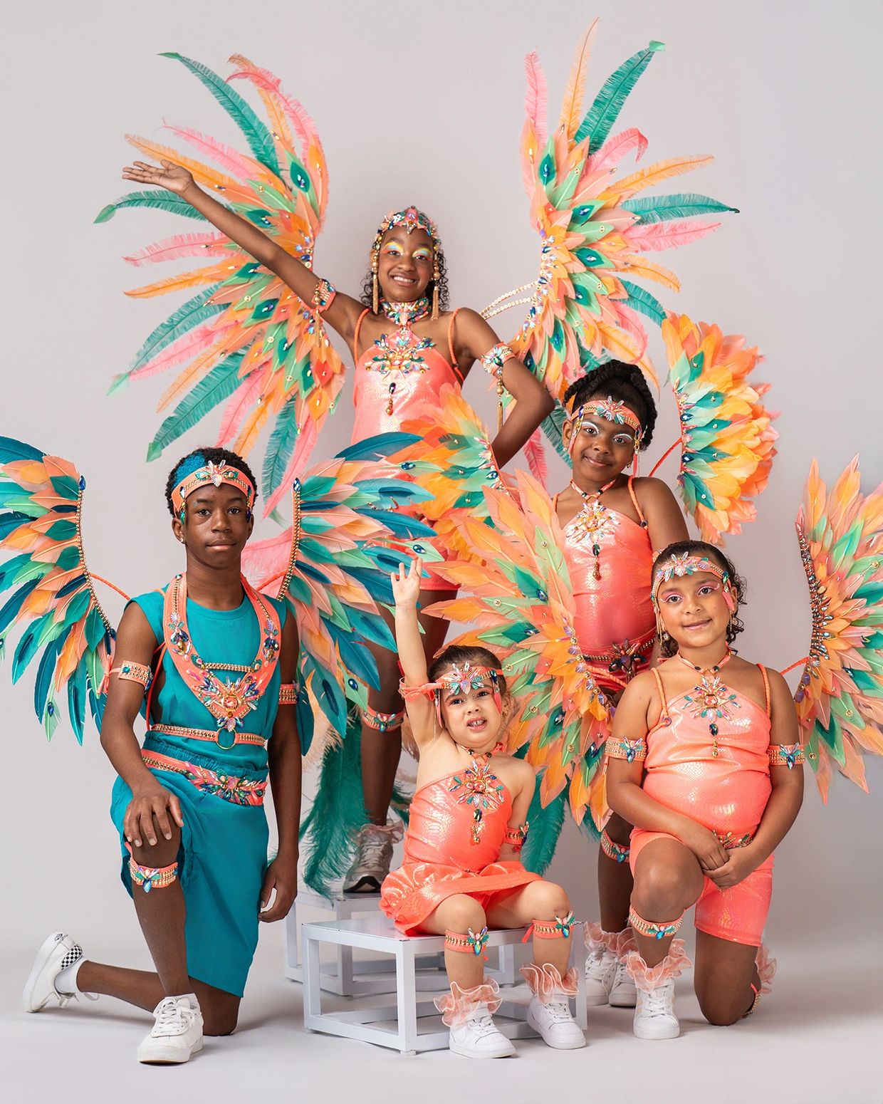 Children in vibrant feathered costumes posing for a festive photo.