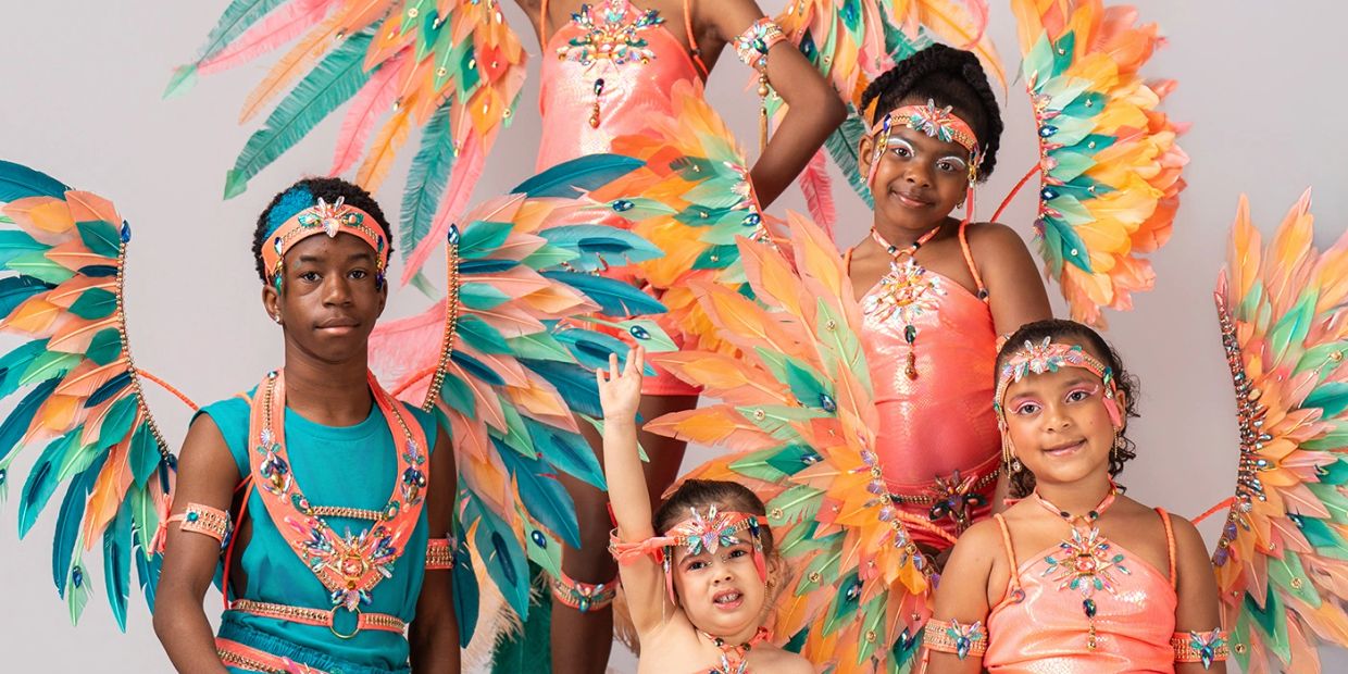 Children in vibrant feathered costumes posing for a festive photo.