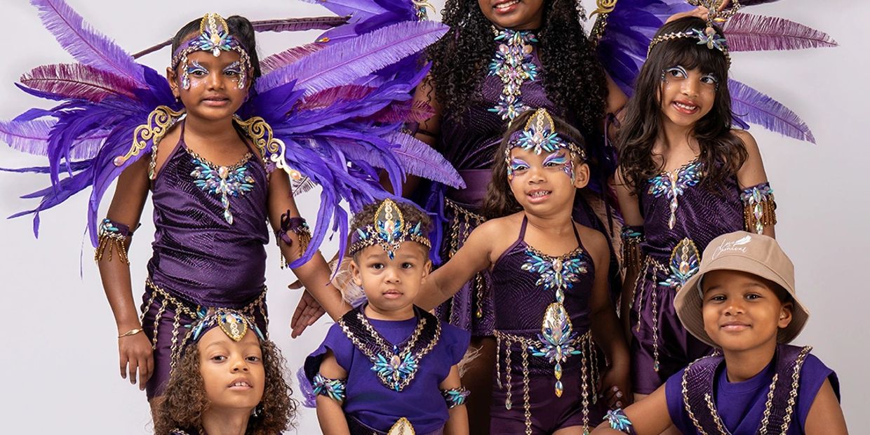 Group of children in vibrant purple feathered costumes posing together.