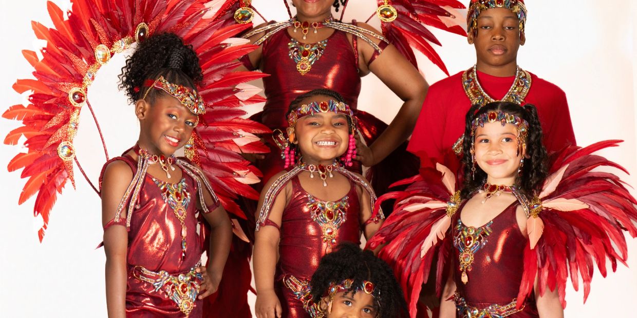 Children dressed in vibrant red carnival costumes with feathered headdresses.