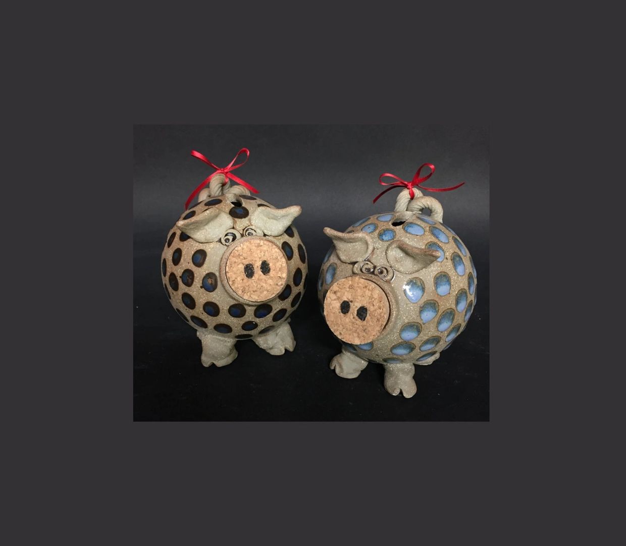 Two decorative pig-shaped ornaments with red ribbons.
