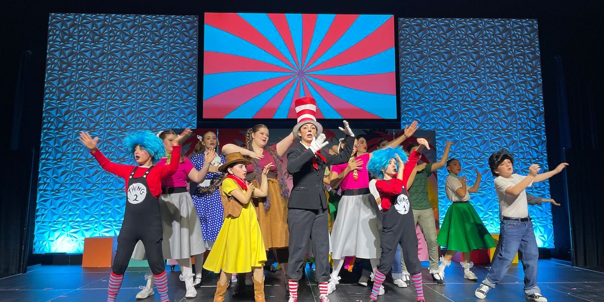 Children performing a colorful stage play with vibrant costumes and animated expressions.