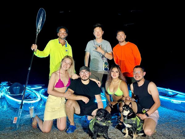 A group of individuals standing around kayaks on a beach