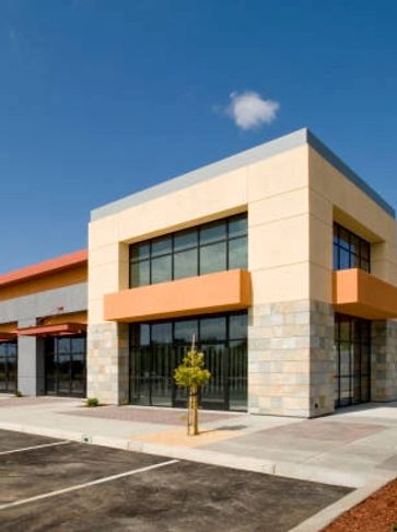 Modern commercial building with large windows and a clear blue sky.