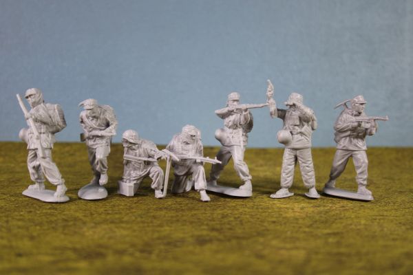 Seven unpainted plastic toy soldiers in various poses.