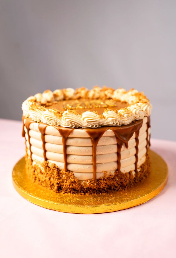 Layered caramel drip cake with cream frosting and crumb base.