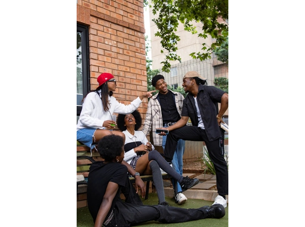 Woman holding microphone talks to smiling young people in a casual setting.