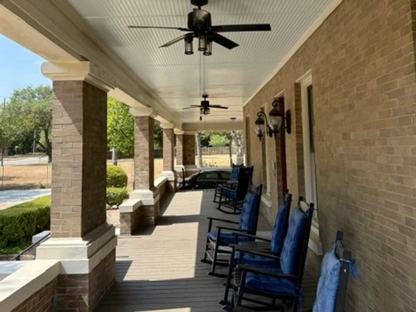 A porch with rocking chairs and ceiling fans.