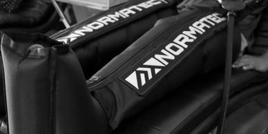A person sitting with their legs inside NormaTec compression boots for recovery therapy.