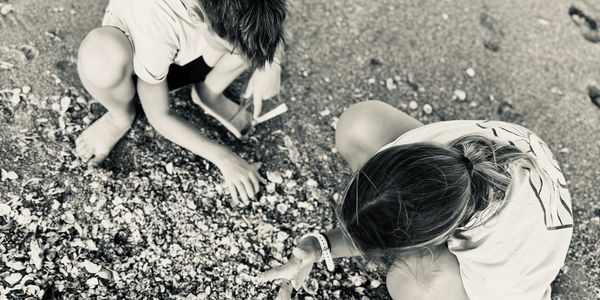 Two children playing and exploring on a rocky beach.