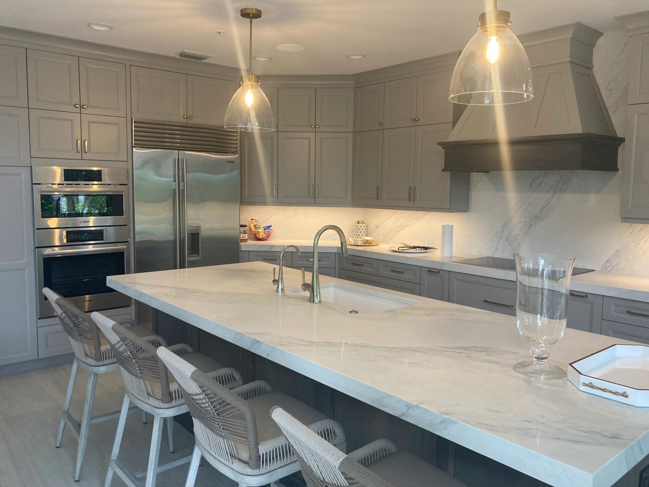 Modern kitchen with gray cabinetry and marble countertops.