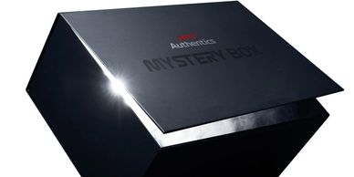A sleek black mystery box with a partially open lid and a glowing light inside.