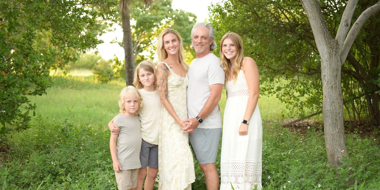 Key West photo session of a beautiful family of 5 dressed in white in the woods by the beach.