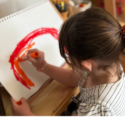 Girl child, painting with orange and red on white paper