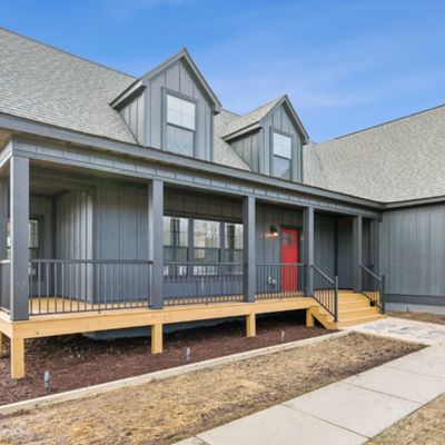 Modern gray house with a red front door and a spacious porch.