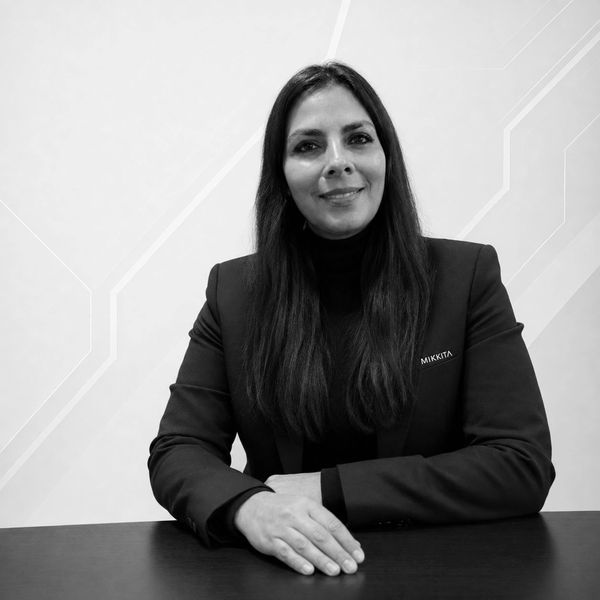 Mujer con chaqueta negra y cabello largo sonriendo.