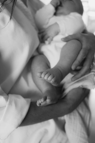 Parent holding a baby close in black and white.
