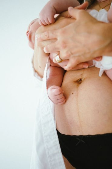 A mother holding her newborn against her bare belly with a visible linea nigra.