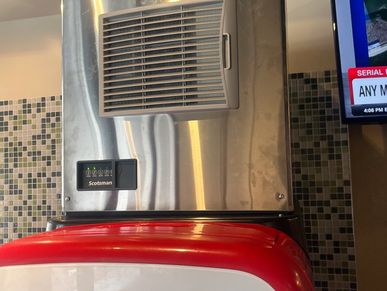 Scotsman ice machine on top of a red and white drink dispenser with tiled wall.