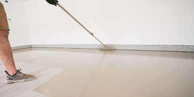 Applying basecoat (polyurea not epoxy) on concrete garage floor using a roller.