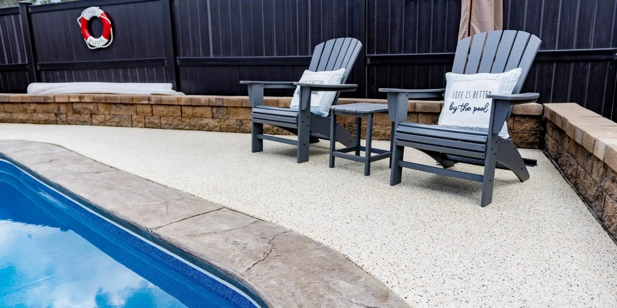 Poolside area with two gray Adirondack chairs on an epoxy deck.