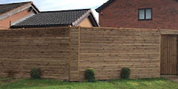 Wooden fence with small plants in front of houses.